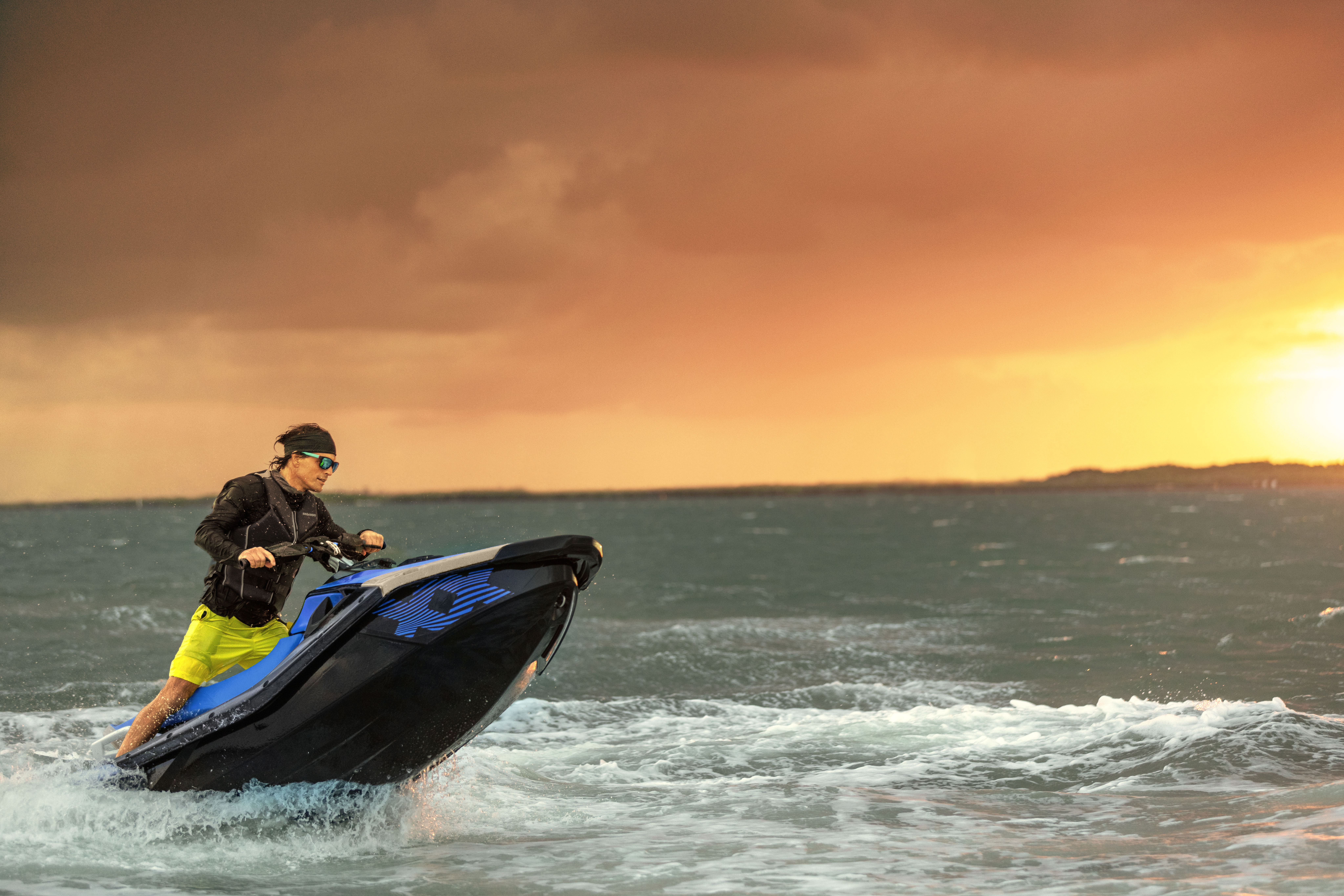 Nuori mies ajamassa Sea-Doo Spark Trixx vesijetillä auringonlaskun aikaan. Vesijetin keula on hieman pystyssä.